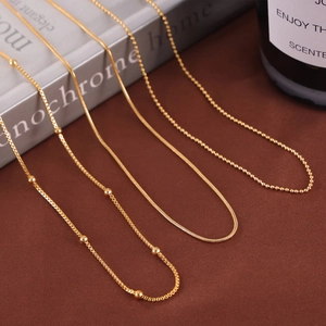 Minimalist gold plated titanium steel necklaces with diverse chain patterns on dark fabric