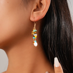 Close-up of beaded star tassel earring on model featuring colorful stones and gold chain