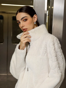 Detailed texture of white faux fur jacket with high collar and silver zipper detail