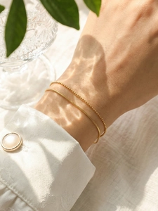 Close-up of double-layered 18k gold-plated snake and bead chain bracelet on a wrist