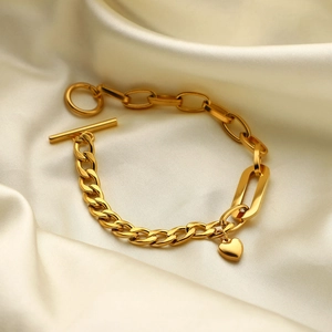 Detail of 18K gold-plated Cuban chain bracelet with heart pendant and OT clasp on silk