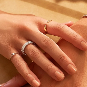 Close-up of layered S925 sterling silver rings featuring a minimalist cross-over design