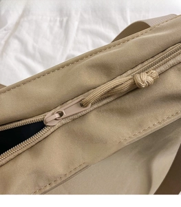 Detail of smooth zipper closure and woven puller on the khaki large capacity tote bag