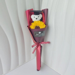 Detail of graduation bear plush with sunflower soap flower in dark red gift wrap