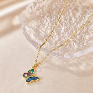 Macro shot of colorful butterfly pendant with gradient shell wings on golden chain