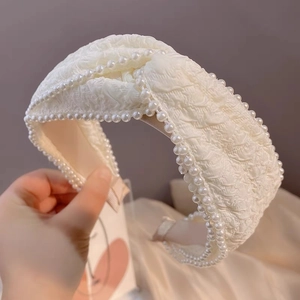 Detail of elegant cream pearl headband with ruched fabric and top knot design