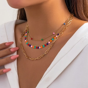 Close-up of layered gold chains with colorful oil drip pendants and eye-catching butterfly charms