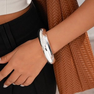 Close-up of polished silver geometric thick metal bracelet on wrist with modern finish