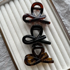 Close-up of tortoise, black, and amber bow hair clips on a beige velvet jewelry tray