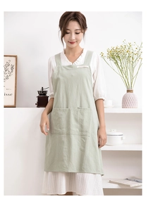 Detail of light green cotton linen apron with cross-back straps and front pockets