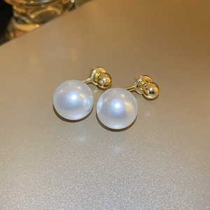 Macro shot of gold-plated minimalist pearl earrings with a sleek warm golden finish