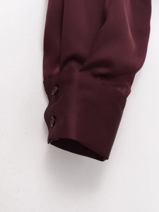 Close-up of double-buttoned cuffs on burgundy satin shirt with smooth fabric texture