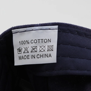 Detail of 100% cotton material tag and washing instructions on a navy baseball cap