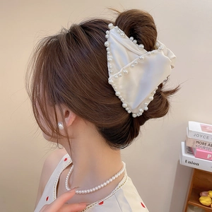 Vue détaillée d'une pince à cheveux en satin blanc crème avec bordure en perles fines