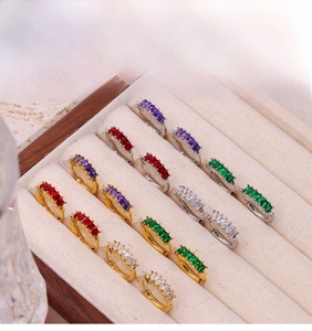 Detailed macro of small hoops with colorful rectangular zircons in a jewelry box