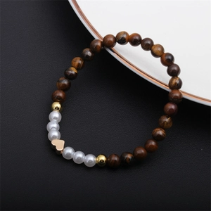 Détail du bracelet en perles d'oeil de tigre avec breloque coeur sur cuir noir