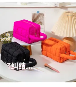 Close-up of quilted makeup bags in rose, orange, and black with metal zippers