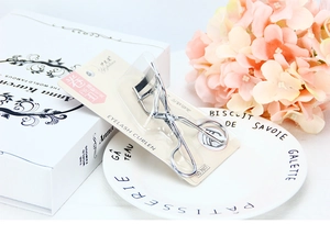 Close-up of a professional silver 3D eyelash curler in retail blister card packaging