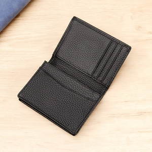 Genuine black lychee leather business card holder with multiple slots on wood background