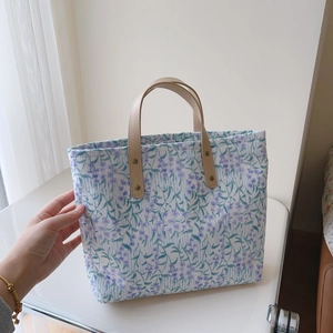Détail d'un sac cabas floral avec imprimés violets, anses en cuir et rivets