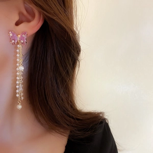 Detailed view of elegant pink butterfly tassel earrings with pearls and crystals on model