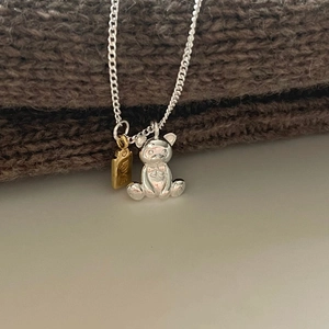 925 Sterling silver teddy bear necklace with gold LOVE tag on a brown knit background