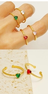 Detail of four colorful zircon heart rings with gold plated hammered texture finish