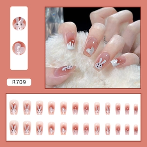 Detail view of caramel amber press-on nails with 3D rabbits and heart glitter accents