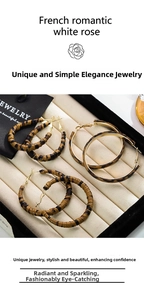 Detailed close-up of three pairs of leopard print hoop earrings in a jewelry gift box
