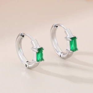 Vue macro de boucles d'oreilles anneaux argentés avec pierres précieuses vertes rectangulaires