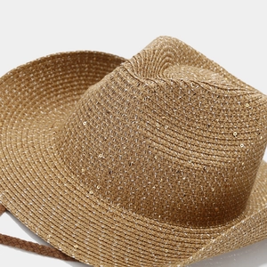 Detail of straw sun hat with gold sequins, woven texture and brown chin strap
