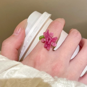Detail of pink resin flower ring with green band worn on finger in a daily life setting