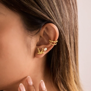 Close-up of bird stud earrings and opal stone set with 18K gold-plated ear cuff on ear