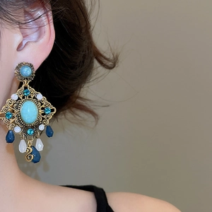 Macro side view of vintage bohemian turquoise earrings with golden beads on model