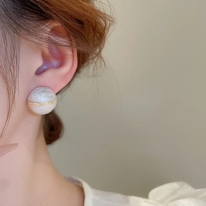 Close-up of vintage geometric gold-plated stud earring with marble texture on model's ear