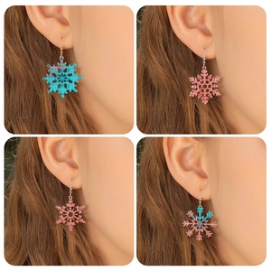 Handmade snowflake resin earrings in blue and pink, shown on model for size and style