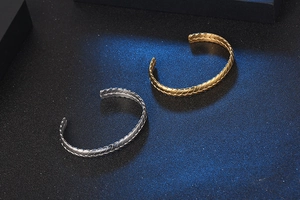 Detalle de brazaletes de acero inoxidable en oro y plata con diseño de espiga tejida