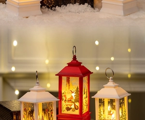 Close-up of vintage Christmas LED lanterns with Santa and snowman scenes on artificial snow