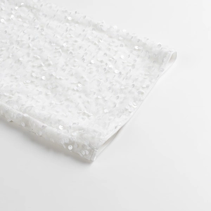 Gros plan détaillé sur les broderies à paillettes blanches de la robe courte