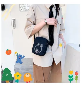 Detail of a black canvas crossbody bag with a cute white line art bunny illustration