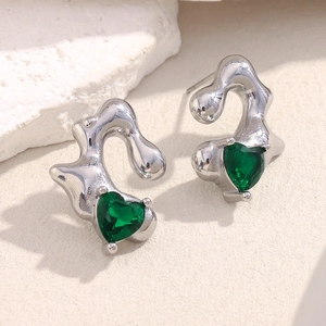 Detail of silver liquid metal earrings with heart-shaped green gemstones on stone