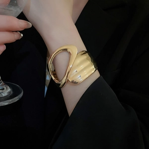 Close-up of a minimalist gold irregular geometric cutout cuff bracelet on a model wrist