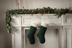 Close-up of dark green knitted Christmas stockings with cable patterns on fireplace
