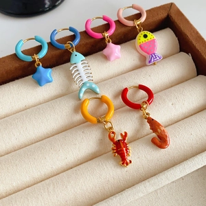 Detailed view of colorful marine life earrings like starfish and fish on beige velvet