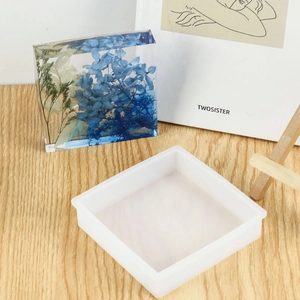 Square silicone coaster mold with DIY resin finished product featuring blue dried flowers