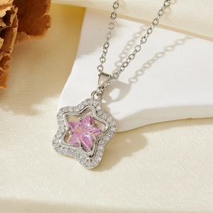 Macro shot of silver star necklace pendant featuring a pink zircon gemstone and crystals