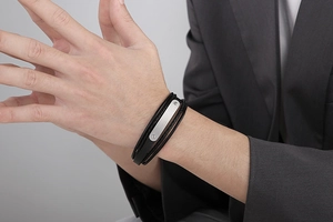 Close-up of a men's multilayer black braided leather bracelet with silver metal plate