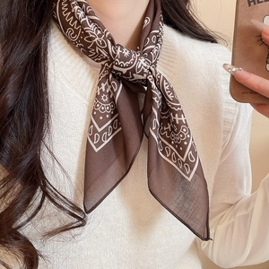 Detail of a dark brown paisley silk scarf necklace on a white knit sweater outfit