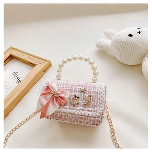 Close-up of pink tweed child handbag with pearl handle, bow, and rhinestone charms