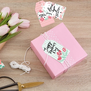Detail of Happy Mother's Day gift tags with pink tulip illustrations on a wooden surface